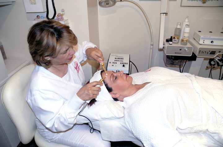 An aesthetician at Berenice giving a client a Myotonology facial toning treatment