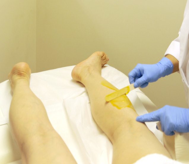 A practitioner at Berenice applying wax to a client's leg